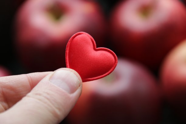 手拿心形苹果为背景的健康食品概念。图片下载