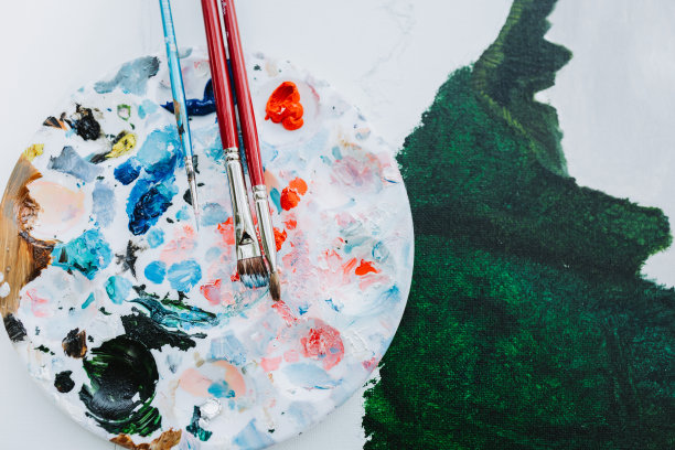 一个圆形的调色板和刷子在画布上画了绿色的油。业余的画家。图片下载