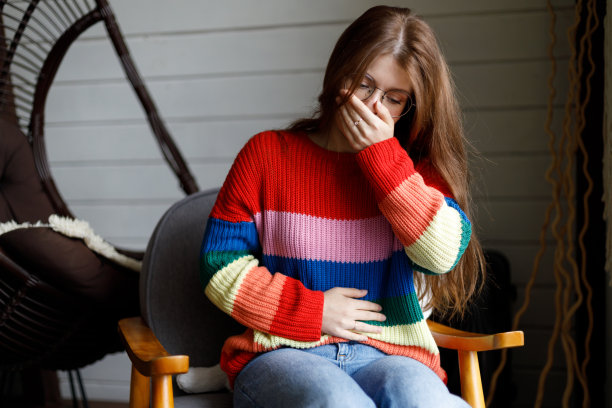 一位年轻女子在家中感到恶心。腹痛，感染。图片下载