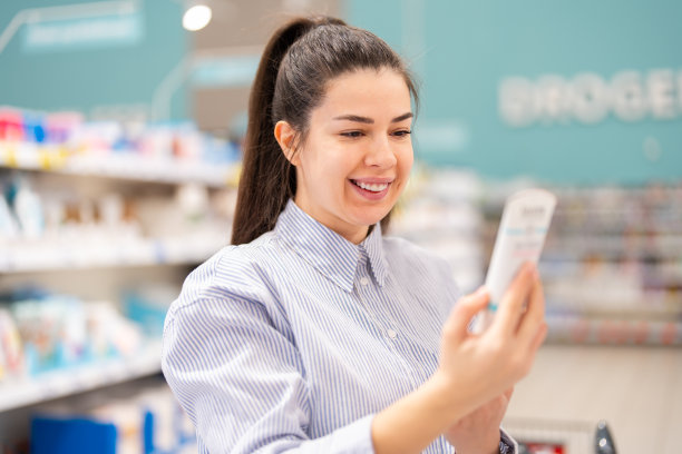 一名年轻女子正在阅读护肤品瓶子上的信息标签图片下载