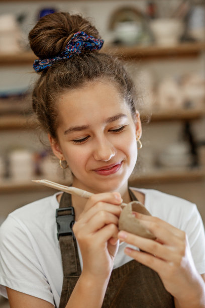 美丽的少女在陶器作坊玩模型粘土。手工和泥塑艺术。近距离图片下载