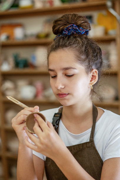 美丽的少女在陶器作坊玩模型粘土。手工和泥塑艺术。近距离图片下载