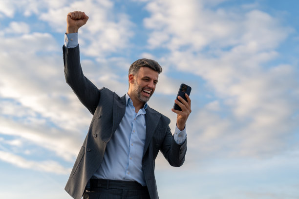 兴奋的男子在商务服使用手机庆祝赢得网上赌博图片下载