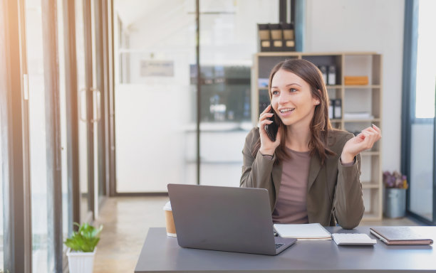 销售，财务，会计，计划，双语女商人正在与代表公司分销商的客户交谈，她在办公桌上用智能手机和笔记本电脑笔和记事本。图片下载