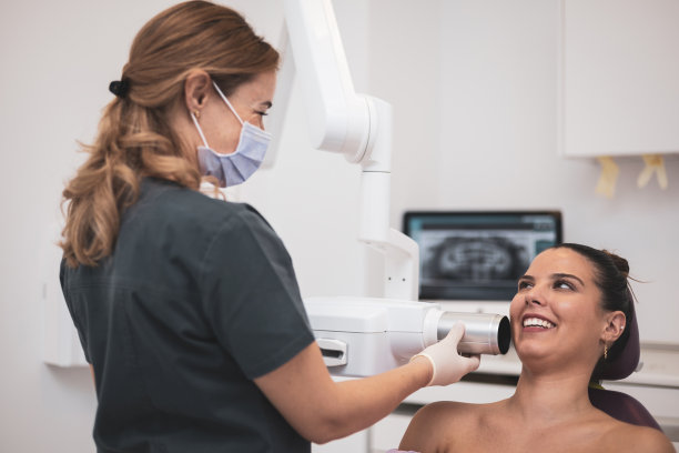 一位女牙医正在进行牙科x光检查研究。病人和专业人士面带微笑地看着对方。图片下载