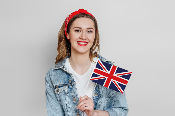 国外的教育。女学生拿着英国国旗，微笑着看着白色背景上的相机图片下载