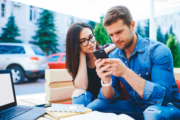 白人千禧男子用手机和女友一起看视频，满足于良好的4G连接，潮人坐在户外看智能手机上的社交网络图片图片下载