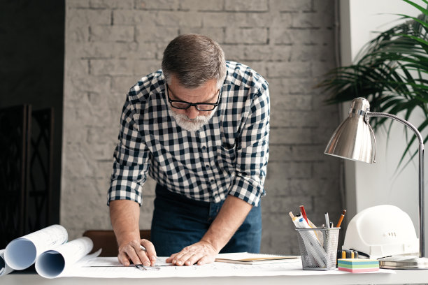 成熟的建筑师工程师设计工作规划理念。商人在办公室工作蓝图的肖像图片下载