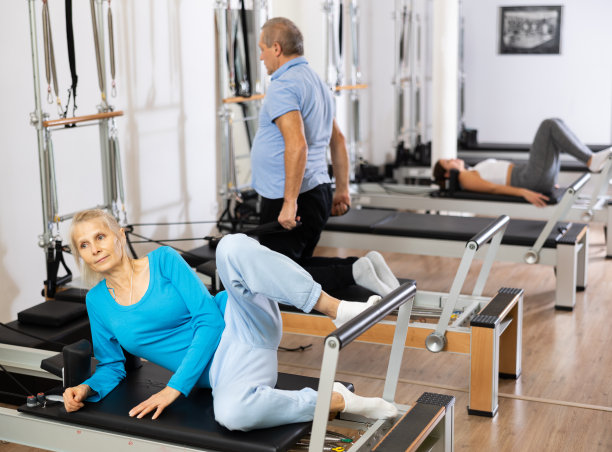 老年妇女在健康健身中心的普拉提床上做背部肌肉锻炼图片下载