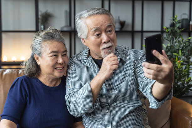 亚洲老年退休夫妇在家里客厅的沙发上一起享受视频电话，亚洲人使用智能手机通信来家庭隔离的概念图片下载
