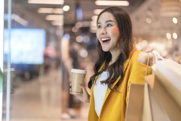 美丽的亚洲女女子女孩是拿着购物袋和咖啡喝，走和愉快享受微笑，在做购物的女性精品百货商场幸福橱窗购物图片下载