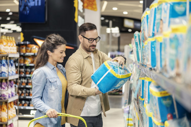 一对年轻的父母站在超市为他们的孩子买尿布。图片下载