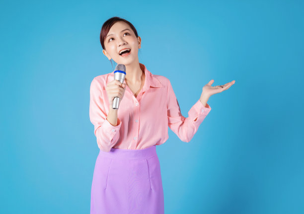 年轻的亚洲女商人在蓝色背景上唱歌图片下载