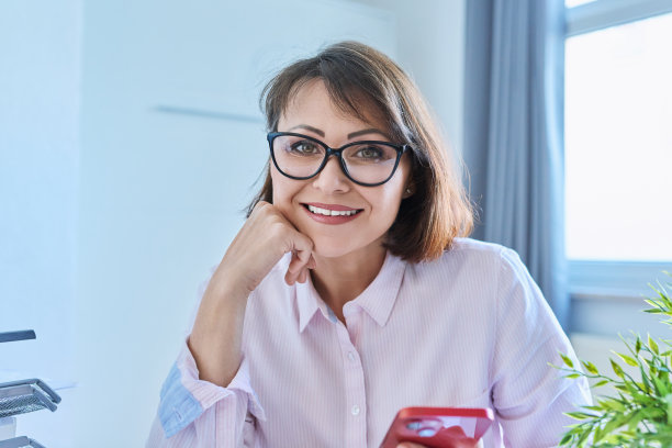 网络摄像头的观点听成熟的妇女坐在办公桌在家庭办公室图片下载