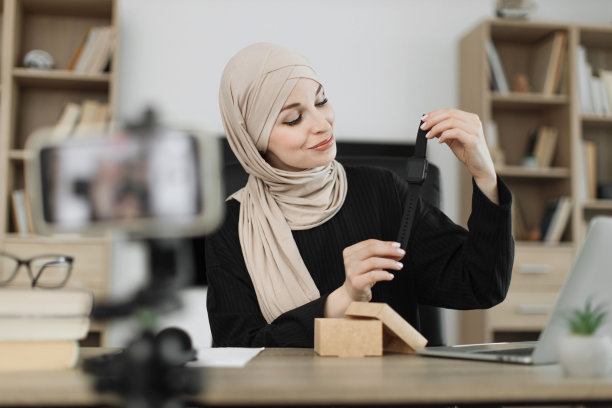 穆斯林妇女一边用新的智能手表开箱，一边做直播。图片下载