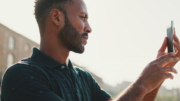 一名年轻男子在港口的智能手机游艇上拍照。图片下载