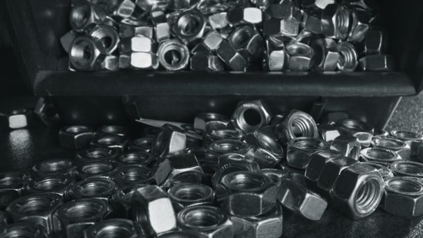 塑料盒和黑色的桌子上有几十个银色的螺母图片下载