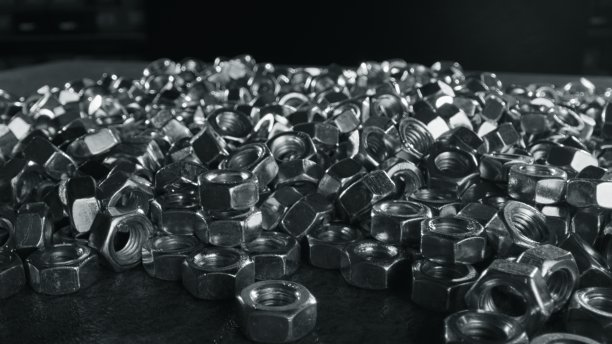 几十个银色的螺母紧固件散落在黑色的桌子上图片下载