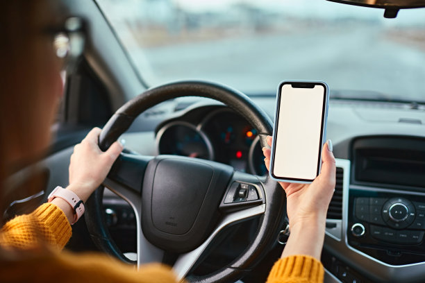 在一辆车里，一个女司机手里拿着空白屏幕的手机模型图片下载