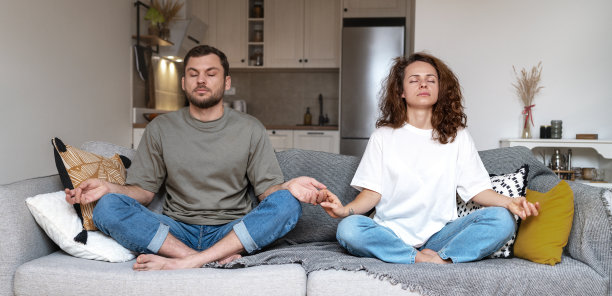 一对夫妇坐在沙发上一起冥想，摆出莲花式。图片下载