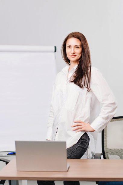 办公室里有个深色头发的女人，手里拿着一块会议板、台式电脑和笔记本电脑图片下载