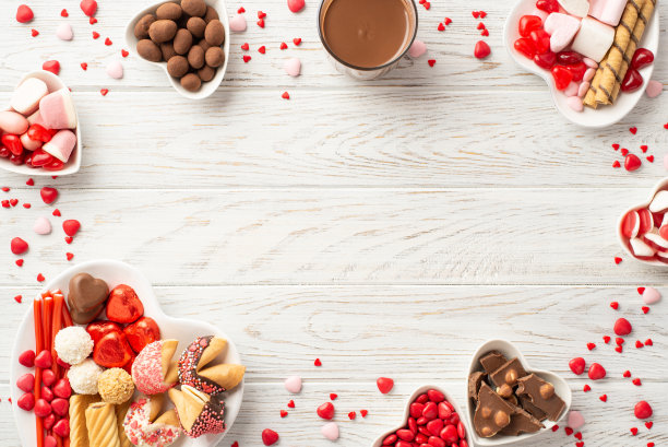 情人节的概念。顶部视图照片的心形盘子与巧克力果冻糖果饼干和一杯热巧克力在白色木桌背景与中间的复印空间图片下载