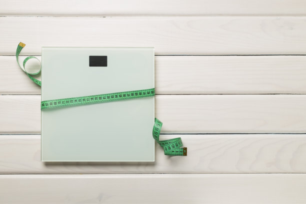 鳞片和卷尺在木制背景，俯视图。减肥概念图片下载