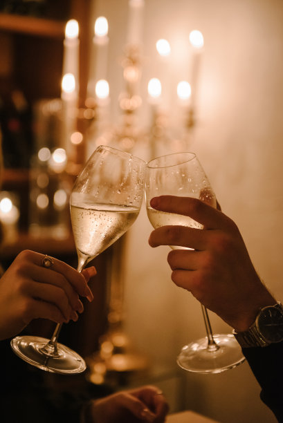 在酒窖烛光下的浪漫约会。相爱的情侣边品酒边喝酒。男人和女人的手在家里拿着酒杯。吐司。情人节的概念。特写镜头图片下载