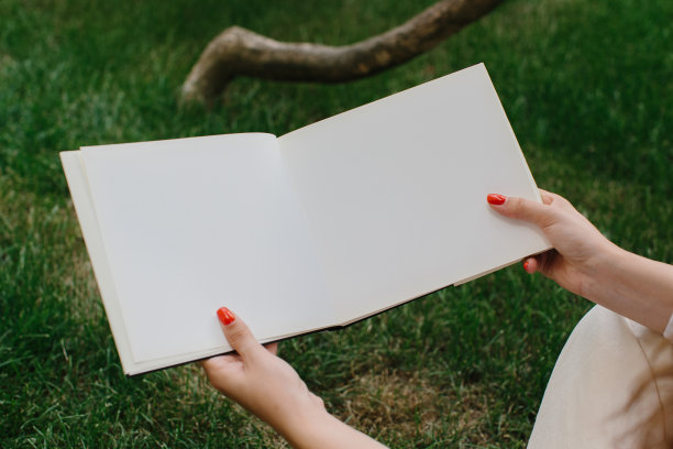 杂志或书籍的形象模型。女孩在咖啡店院子里的草坪上休息，看书。图片下载