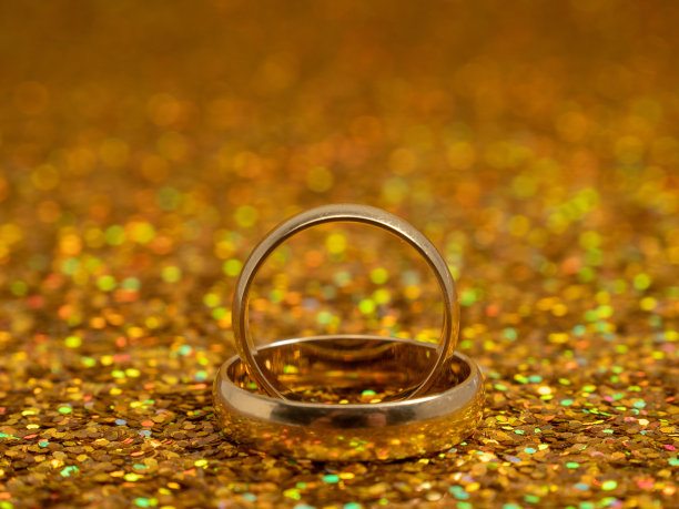金色闪闪的背景上镶嵌着结婚戒指。黄金戒指。图片下载