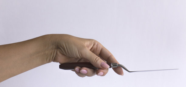 女人拿着调色刀的手特写孤立在白色背景上。图片下载