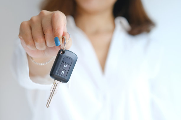 图为，一名女子拿着自己递过来的汽车的智能钥匙，正在示范“送车”。图片下载