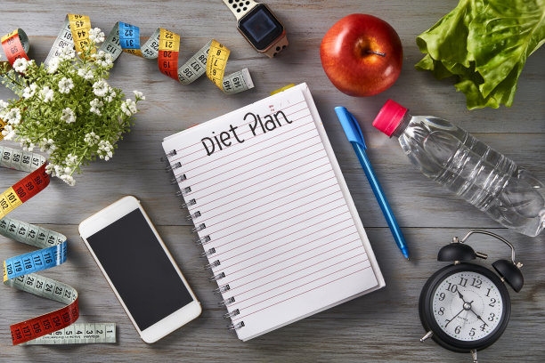 俯视图时钟，记事本与笔，智能手机，卷尺，水瓶，苹果和智能手表在桌子上图片下载