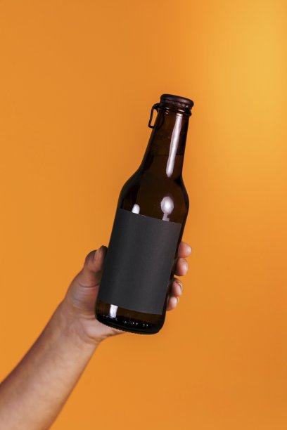 人类手握棕色啤酒瓶对黄色墙壁背景图片下载