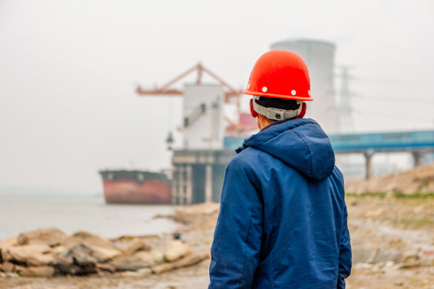 一名男性工程师看着背景中的码头和发电厂图片下载