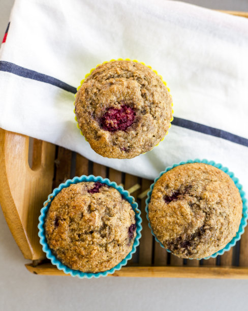 俯视图三个新鲜制作的美味纸杯蛋糕放在一个木制托盘上，上面有一条白毛巾图片下载