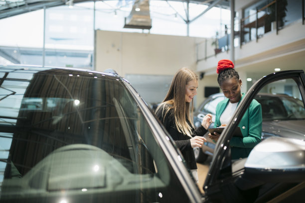 销售经理在汽车经销店与女顾客分享汽车细节图片下载