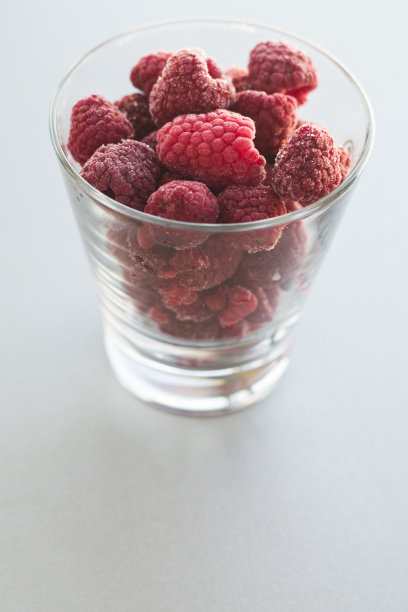 一个装满覆盆子的透明玻璃杯的特写照片图片下载