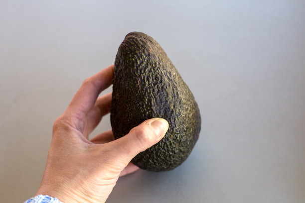 一张灰色桌子背景上一个男人手里的牛油果的照片图片下载