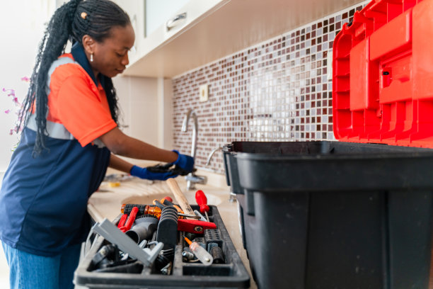 黑人女水管工正在修理一所房子厨房水槽的漏水处图片下载