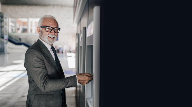 高级企业家使用ATM机的简介视图。年迈的商人在城市通勤时通过电子银行提取现金。图片下载