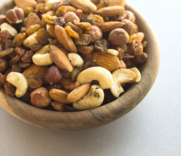 特写照片的不同类型的坚果在一个盘子在一个灰色的桌子上图片下载