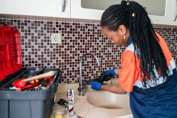 黑人女水管工正在修理一所房子厨房水槽的漏水处图片下载
