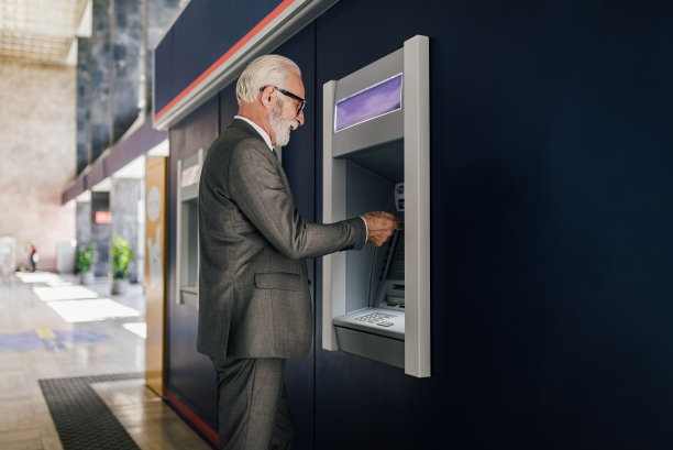 身穿西装的老年商人使用自动取款机提现的剖面图图片下载