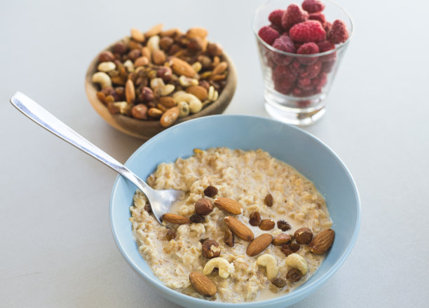 照片的盘子里装满了燕麦混合坚果，盘子里装满了坚果和覆盆子玻璃图片下载