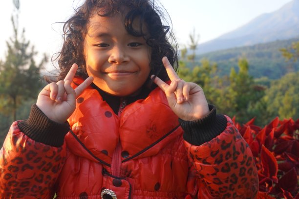 一个快乐的女孩的表情与双手使一个爱的和平标志符号在一个山暑假图片下载