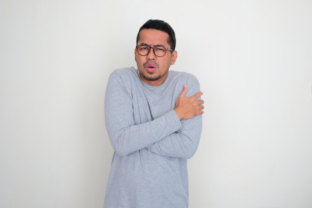 成年亚洲男子穿着长袖衣服感觉寒冷图片下载