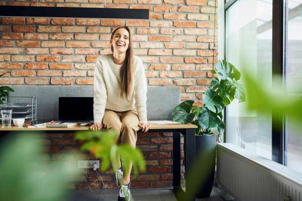 微笑的女企业家坐在小型创业办公室的桌子上图片下载