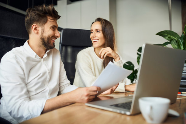 两个快乐的同事在小公司办公室讨论的镜头。随意的商人和女商人在工作中交谈图片下载