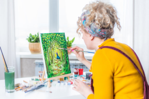 美丽的女孩艺术家在家里的画布上作画图片下载